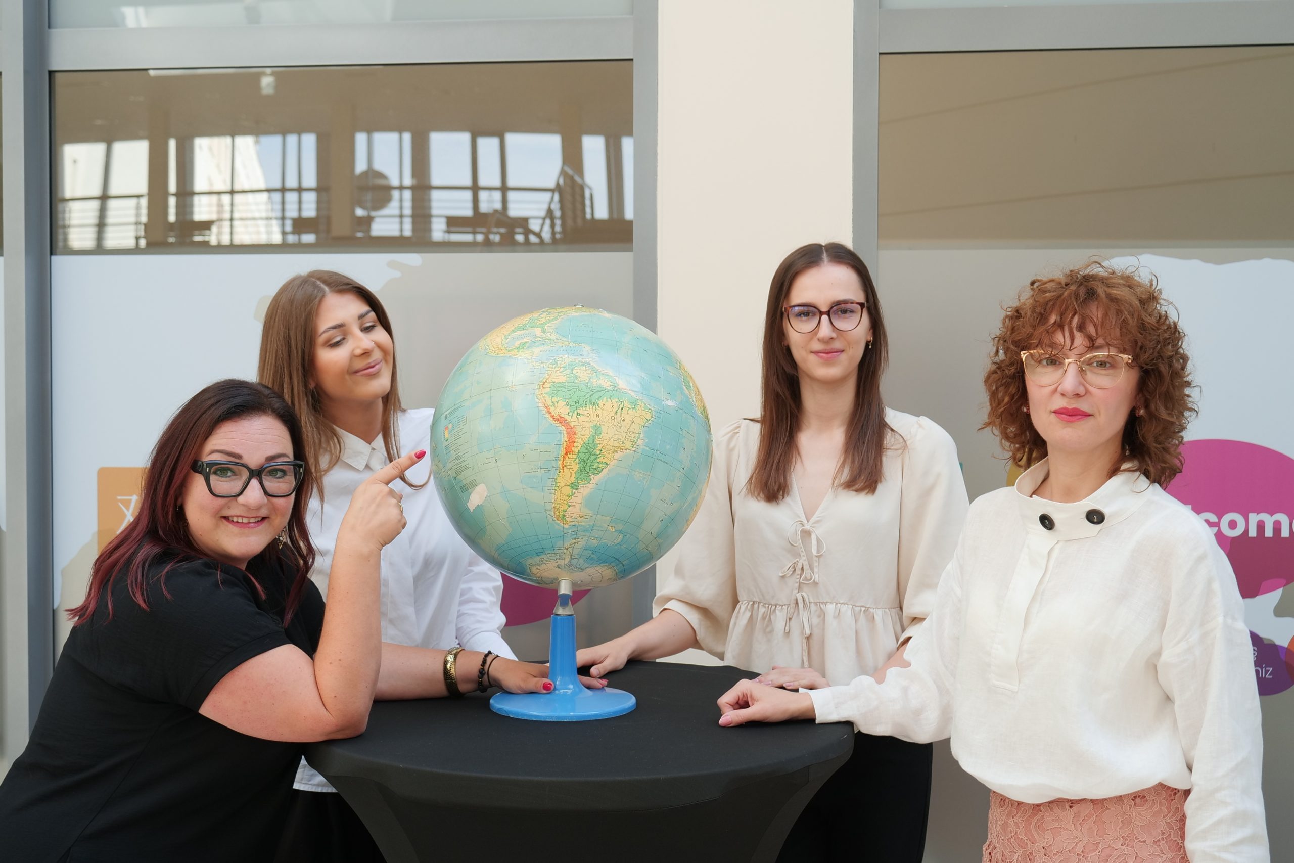 Members of the Welcome Centre team pose around a globe in the Centre's entrance area.