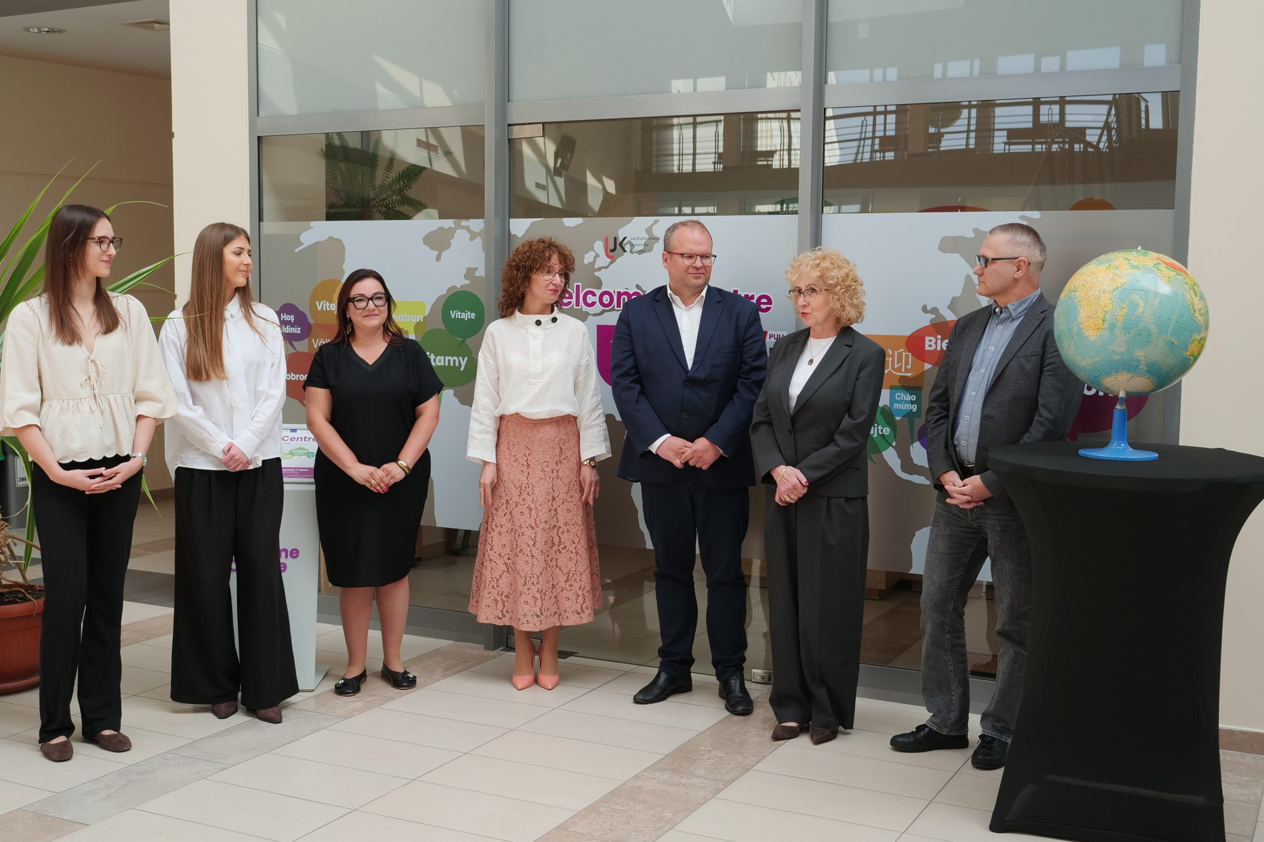 University representatives stand beside a globe during the official opening of Welcome Centre UJK.