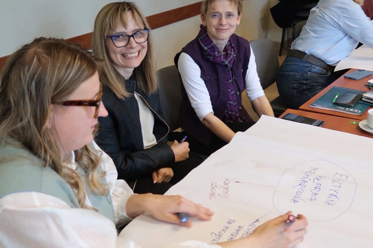 Training participants work together on a large sheet of paper during a group exercise.